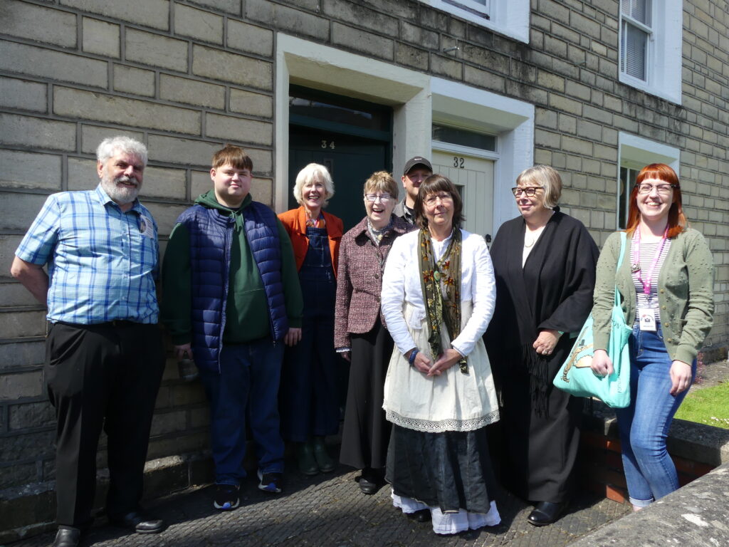 A group of people standing outside the railway village museum.