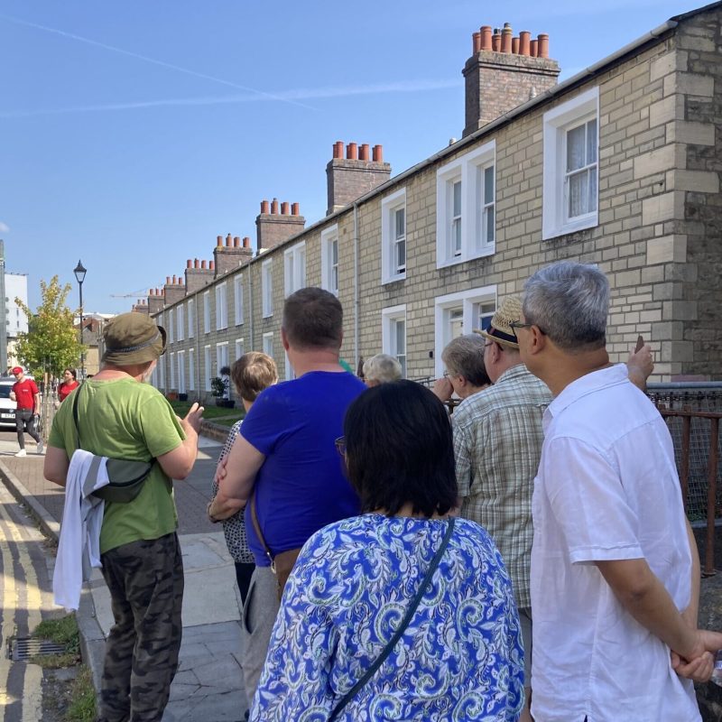 A guide leads a group of tourists through the streets of Swindon Railway Village.